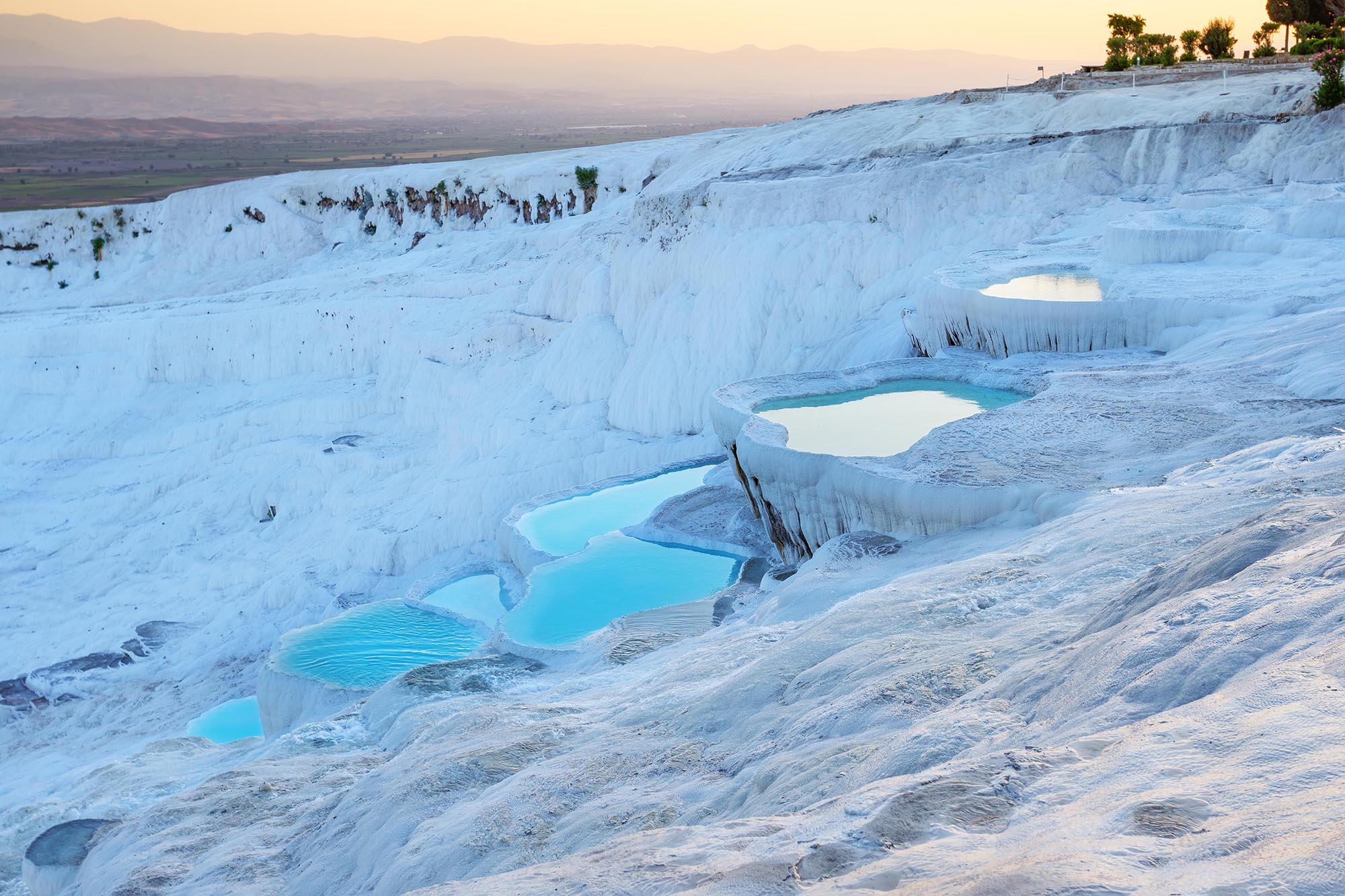 Pamukkale natural travertine terraces filled with blue water at sunset. Denizli, Turkey